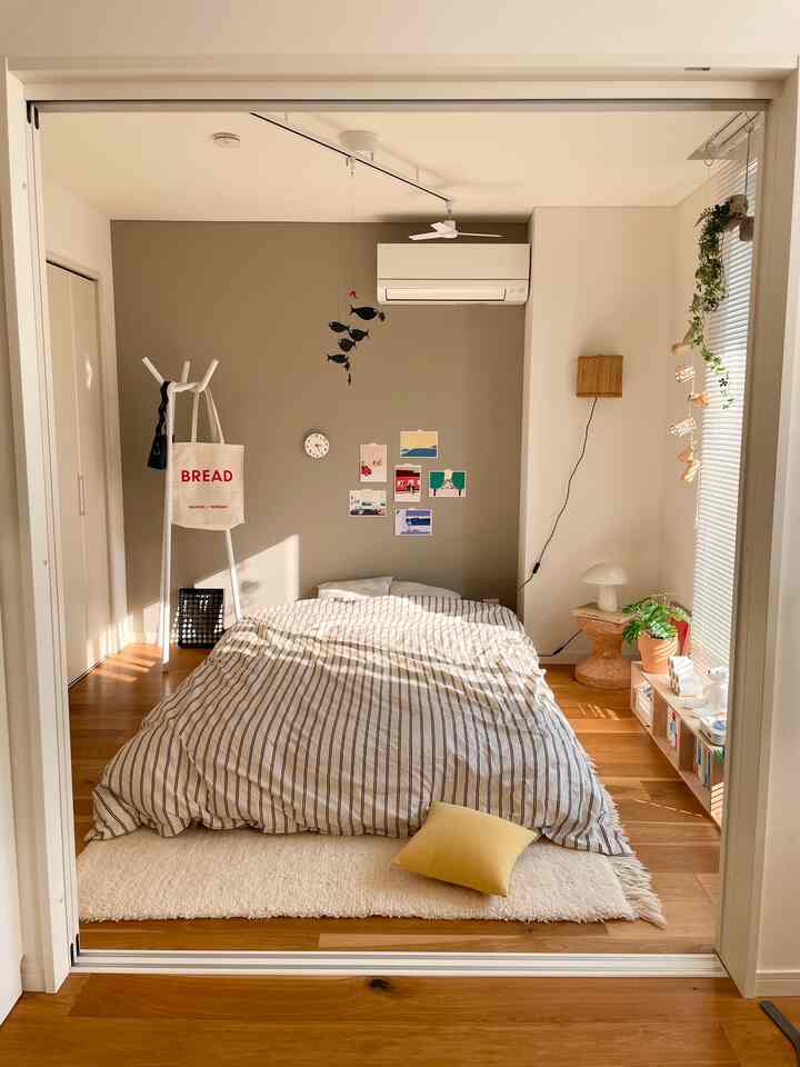 ナチュラルな木目調とホワイトの色調が調和する北欧風の寝室、ストライプの掛け布団カバーと居心地の良いインテリアが配された印象的な空間