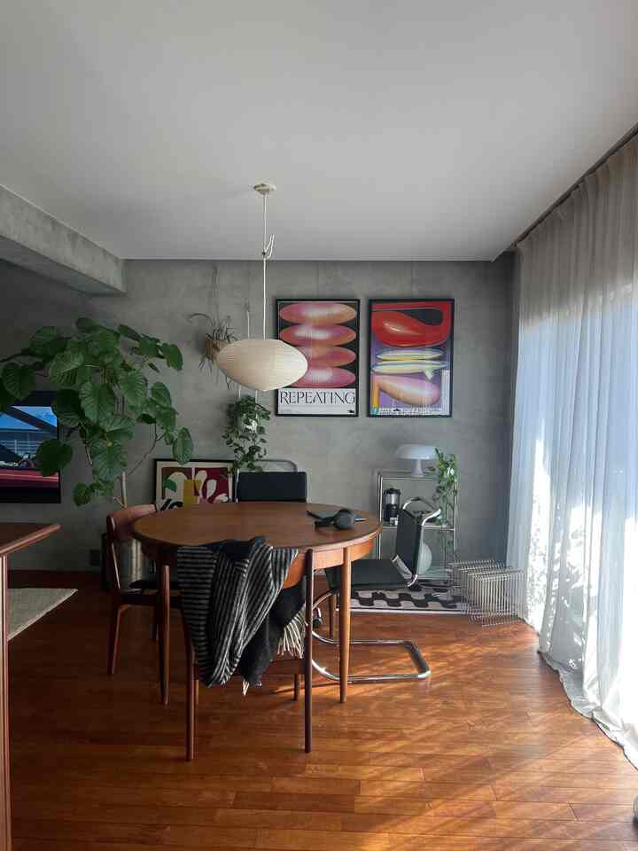 ウッドトーンの床とダイニングテーブル、白いカーテンとペンダントライトが配置されたミッドセンチュリーモダンのリビングスペース