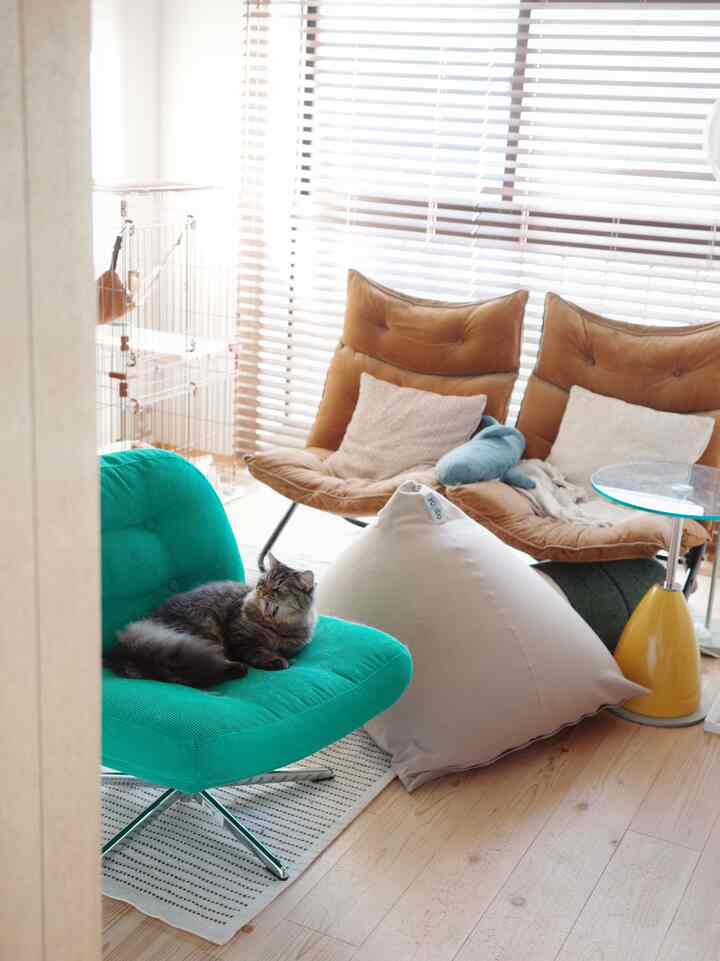 明るく自然な色調のリビング、緑のアームチェアとベージュのビーンバッグ、茶色のソファが配置された雰囲気のあるインテリア