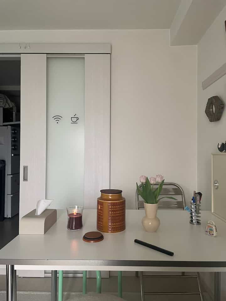 白を基調としたナチュラルな色調の一人暮らし用8畳の部屋、ダイニングテーブルにキャンドルと花瓶が置かれた雰囲気のあるインテリア