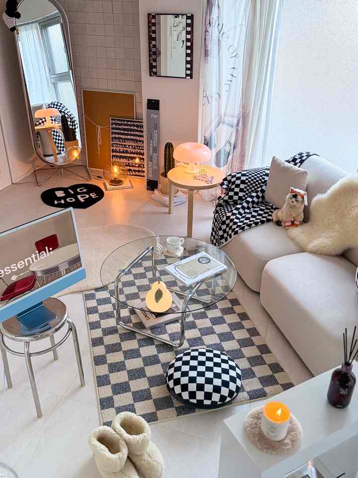 Gray and ivory toned living room featuring a central checkerboard patterned rug and a transparent glass table, creating a simple and cozy atmosphere