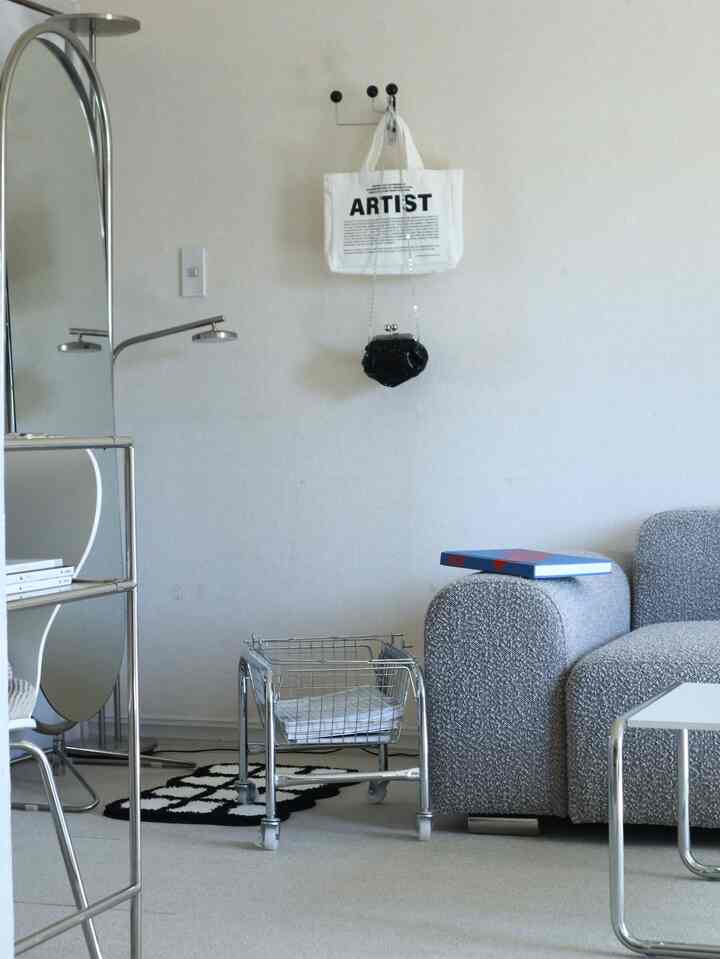 モノトーンとシルバーが調和したモダンなリビング、曲線ソファと収納用シルバーバスケットが配置されたシンプルな空間