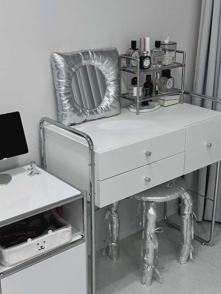 White and silver monotone bedroom vanity with a cushion mirror, featuring a clean mid-century modern style