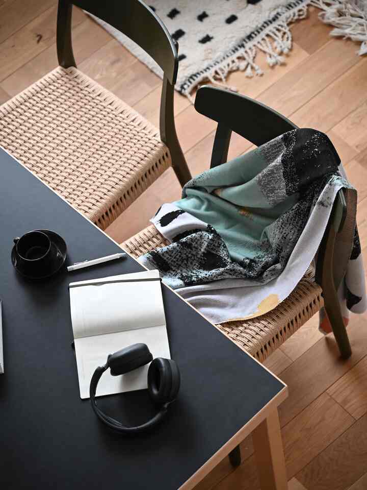 ナチュラルな木目調とダークテーブルがある北欧スタイルの一人暮らし空間、ブランケットとヘッドホンが落ち着いた雰囲気を演出するインテリア