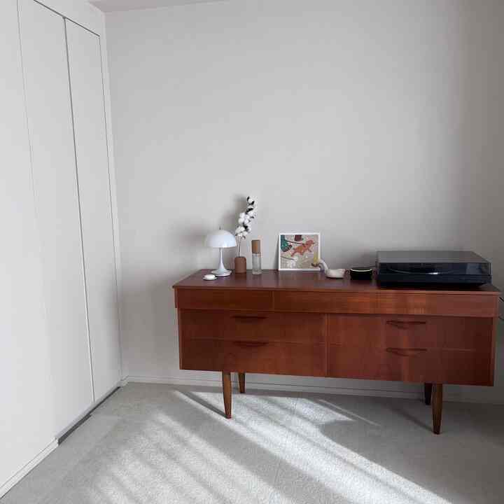 白い壁と茶色のヴィンテージチェストが配置された落ち着いたリビング