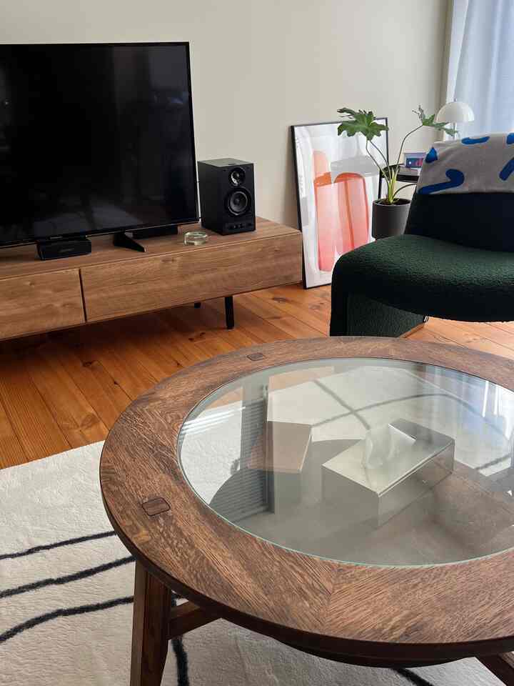 木目調と白色が調和したリビング、丸いローテーブルとダークグリーンのアームチェアが配置された落ち着いた雰囲気のインテリア