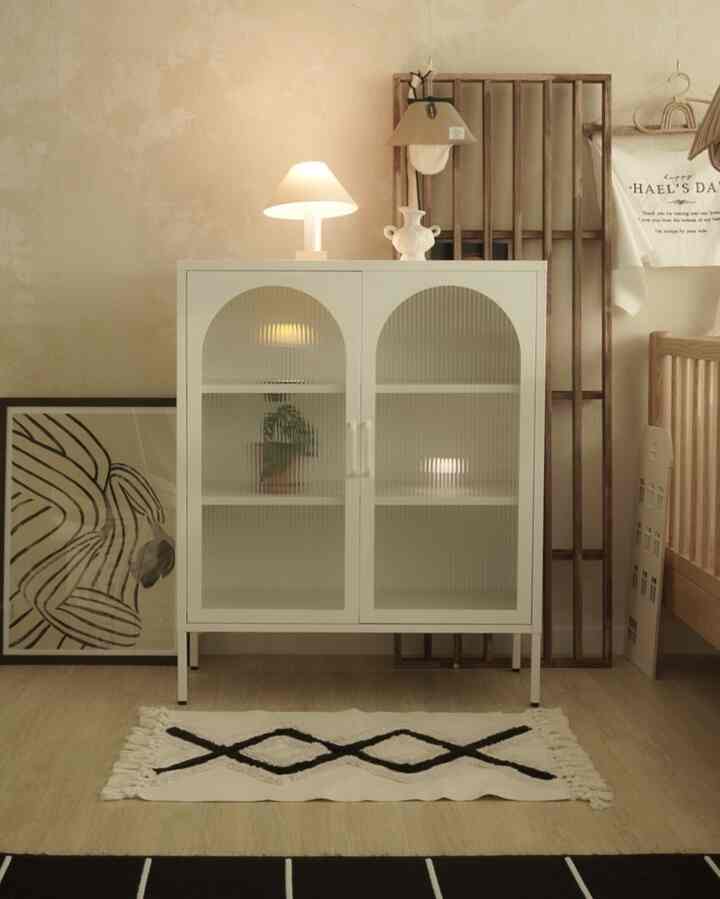 Beige-toned wall and light wood floor in a kids' room, featuring a white frosted glass cabinet with table lamp and small rug in a natural modern style
