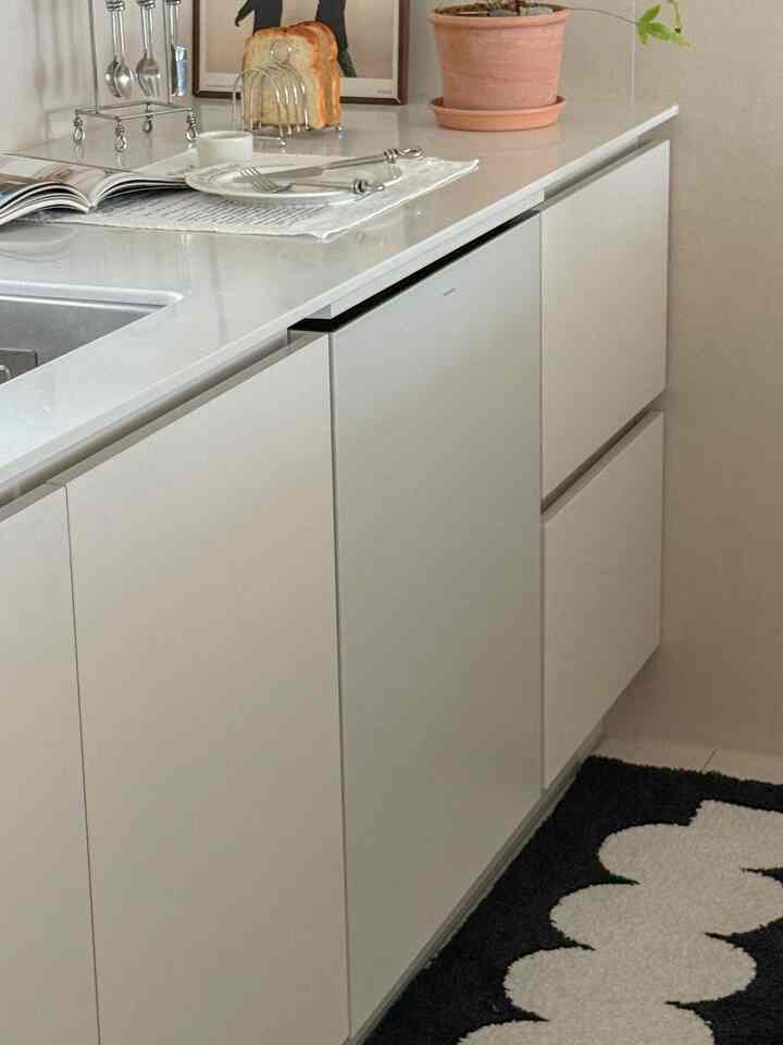 白を基調としたキッチンカウンターに置かれた皿とカトラリーがある清潔感のあるインテリア