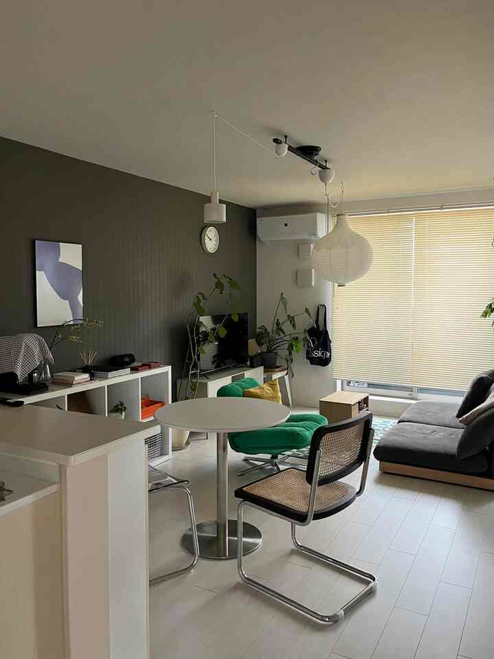 White and gray toned mid-century modern living room featuring gray sofa and green armchair in a neat layout