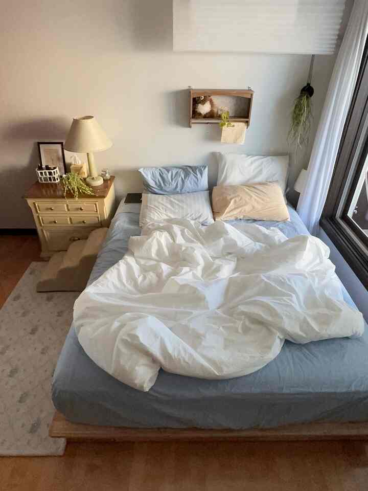 ブルーとホワイトの色調の寝室、ヴィンテージのチェストと清潔な寝具が配置された雰囲気のあるインテリア