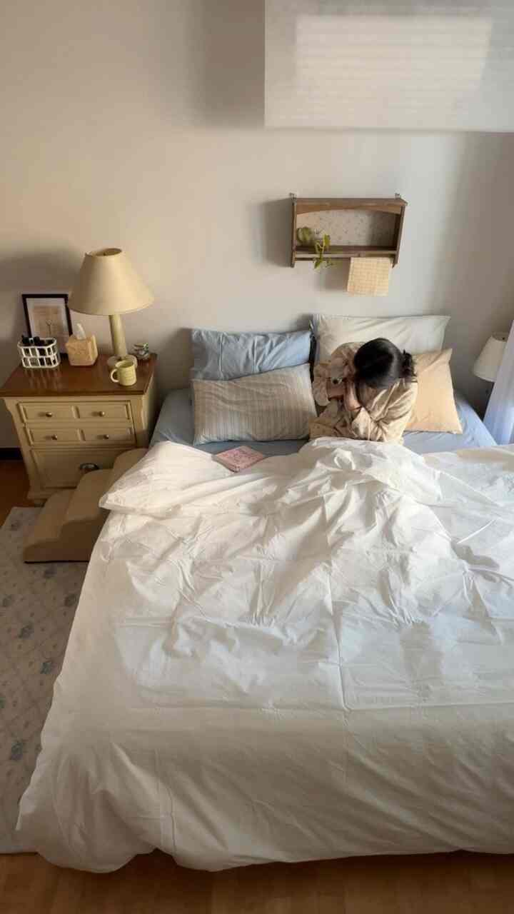 ホワイトとナチュラルカラーの寝室、大きなベッドとヴィンテージのナイトテーブル、犬と一緒にいる温かみのある雰囲気のインテリア