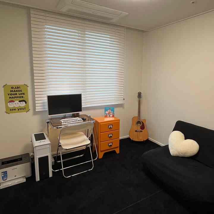 白を基調とした壁とブラインド、黒のラグとソファが配置された、多目的なミッドセンチュリーモダン趣味部屋