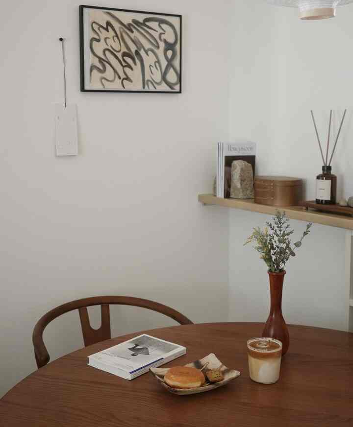 白い壁と温かみのある木目調の家具が配置されたナチュラルなリビング・ダイニング空間で、カフェ風の雰囲気を演出している