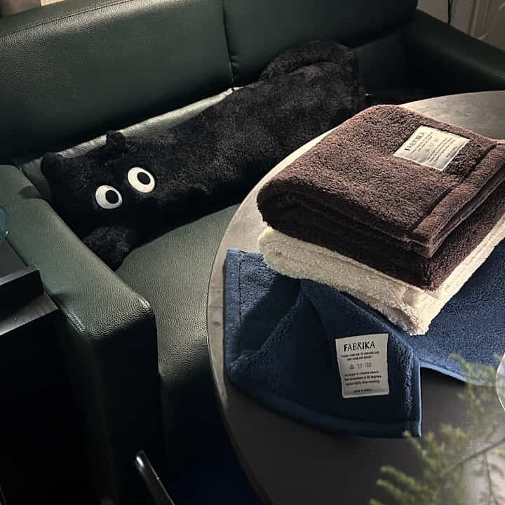 ブルーとブラウンのタオルがテーブルに整然と置かれた、モダンなバスルームの雰囲気のあるインテリア