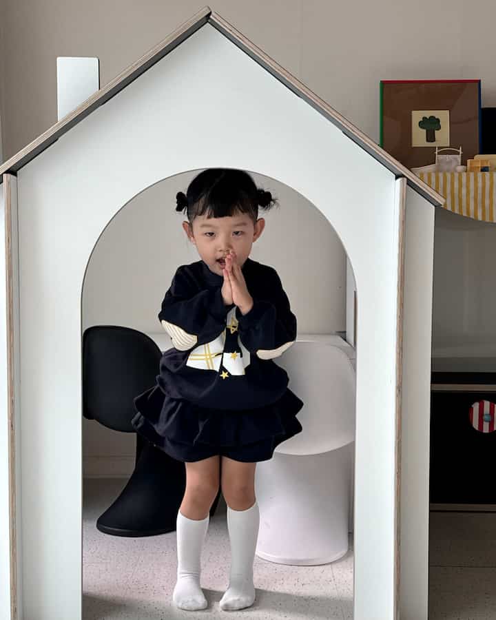 White-toned kids' room featuring a house-shaped room divider partition, kids' desk, and chairs creating a cozy interior
