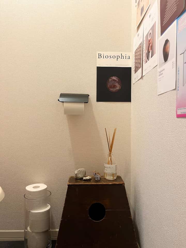 White-toned restroom space featuring a wooden box with diffuser and small stones, and a pet house-like furniture presenting a cozy atmosphere