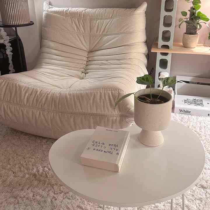 A white and natural-colored living room featuring a beige sofa and round white coffee table creating a cozy atmosphere