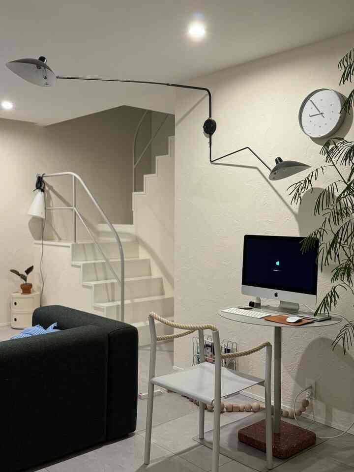 White and gray tone studio apartment home office space featuring simple modern desk and chair in a clean living room