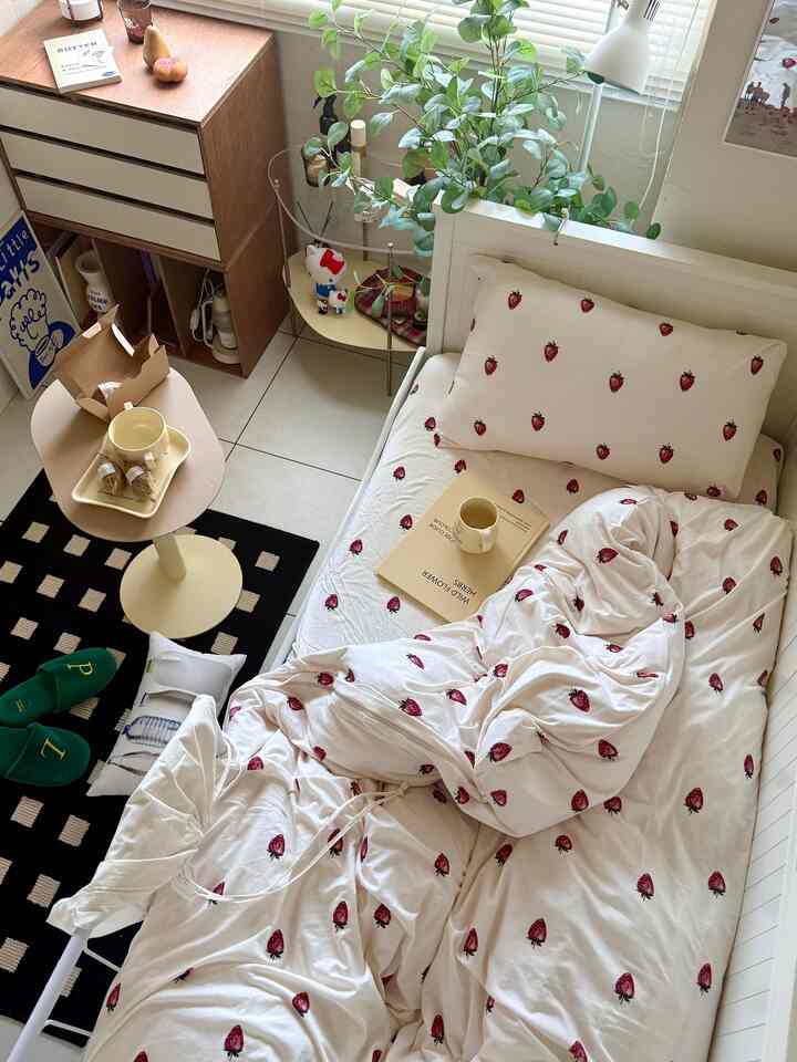 White and natural tone bedroom featuring strawberry printed bedding and round coffee table, creating a cozy space