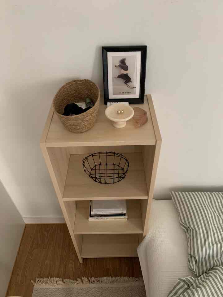 ナチュラルカラーとホワイトの寝室、本棚と枕が配置された雰囲気のある空間