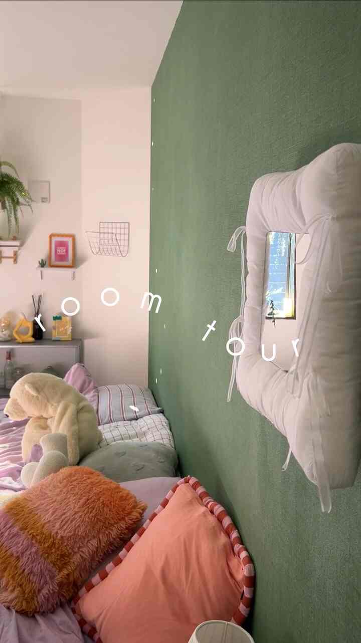 緑色のアクセント壁と多彩なクッションが配置された温かみのある寝室空間