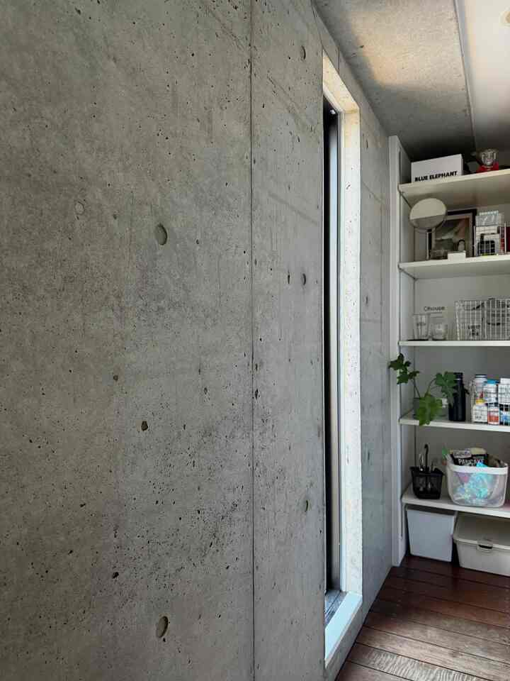 Narrow space featuring natural wood flooring and concrete walls with gap storage shelving unit