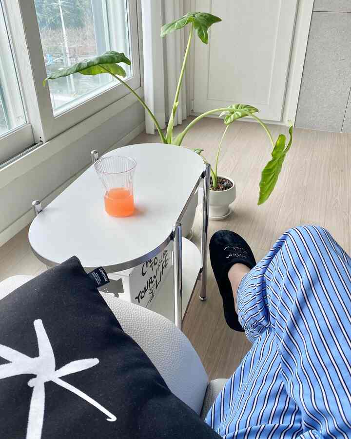 Beige wood flooring with white side table, black cushion on sofa in bright living room space