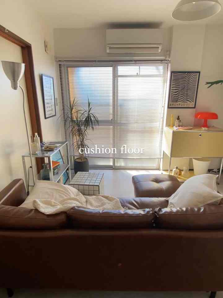 ブラウンのレザーソファとオットマンがある明るく居心地の良い1DKのリビング、ミッドセンチュリーモダンスタイルでまとめられたインテリア