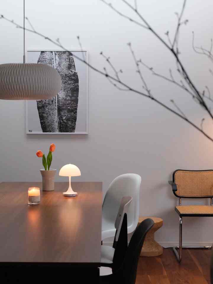 木目調のテーブルと白い壁が調和したモダンなダイニング、キャンドルと照明が暖かい雰囲気を演出