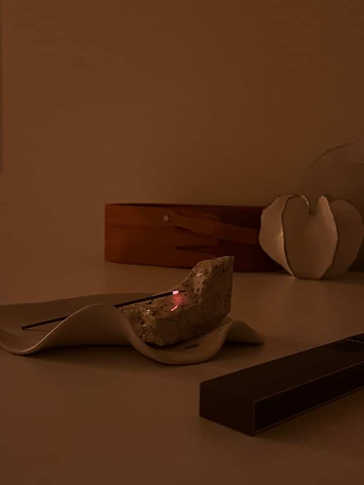 温かみのある木目調と白いテーブルの上に、アロマティックなインセンスホルダーが配置された雰囲気のあるインテリアスペース