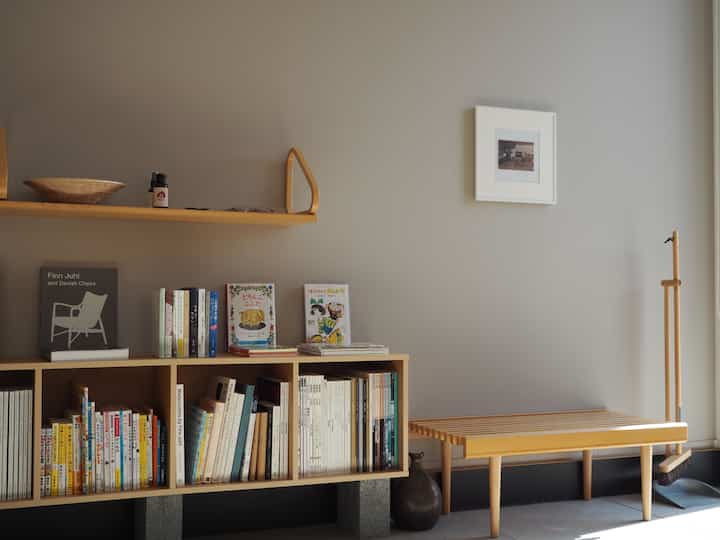 Natural wood tone and beige wall Nordic-style entrance reading space featuring shelf, bookshelf, and bench with a simple atmosphere