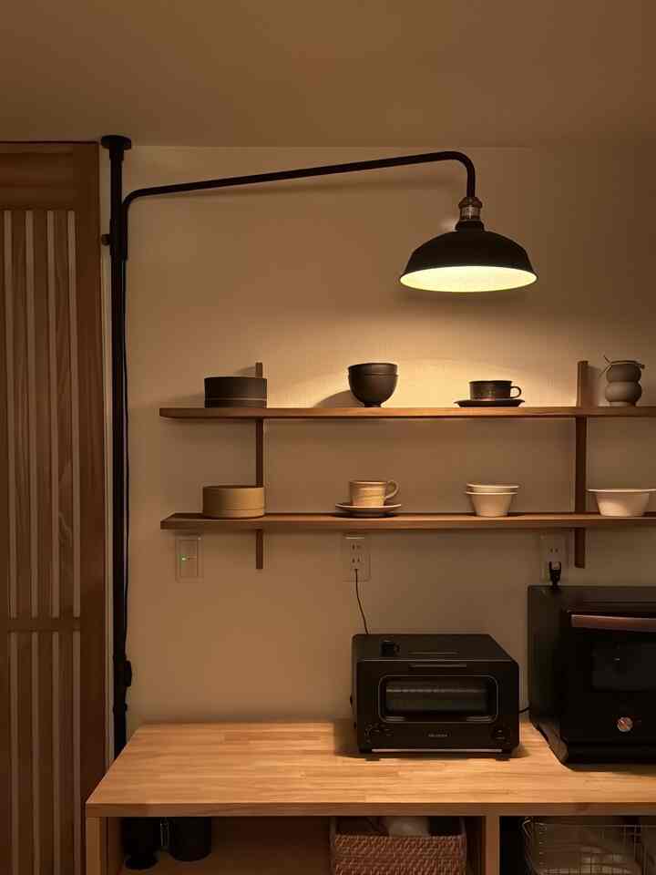 暖かい木目調と黒の壁照明が調和したキッチン、素朴な棚とトースターが配置された雰囲気のあるインテリア