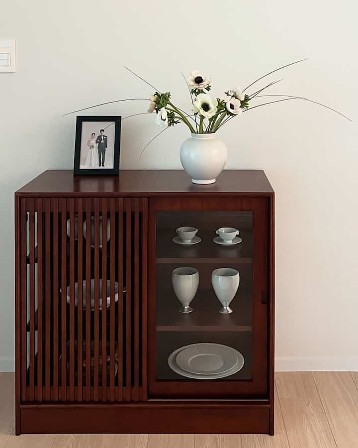Beige-tone room featuring a walnut cabinet with white vase on top, showcasing a simple and elegant interior