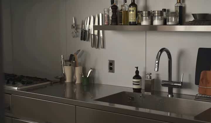 モダンなステンレス素材のキッチン、シンクと調理器具が整然と配置された雰囲気のあるインテリア