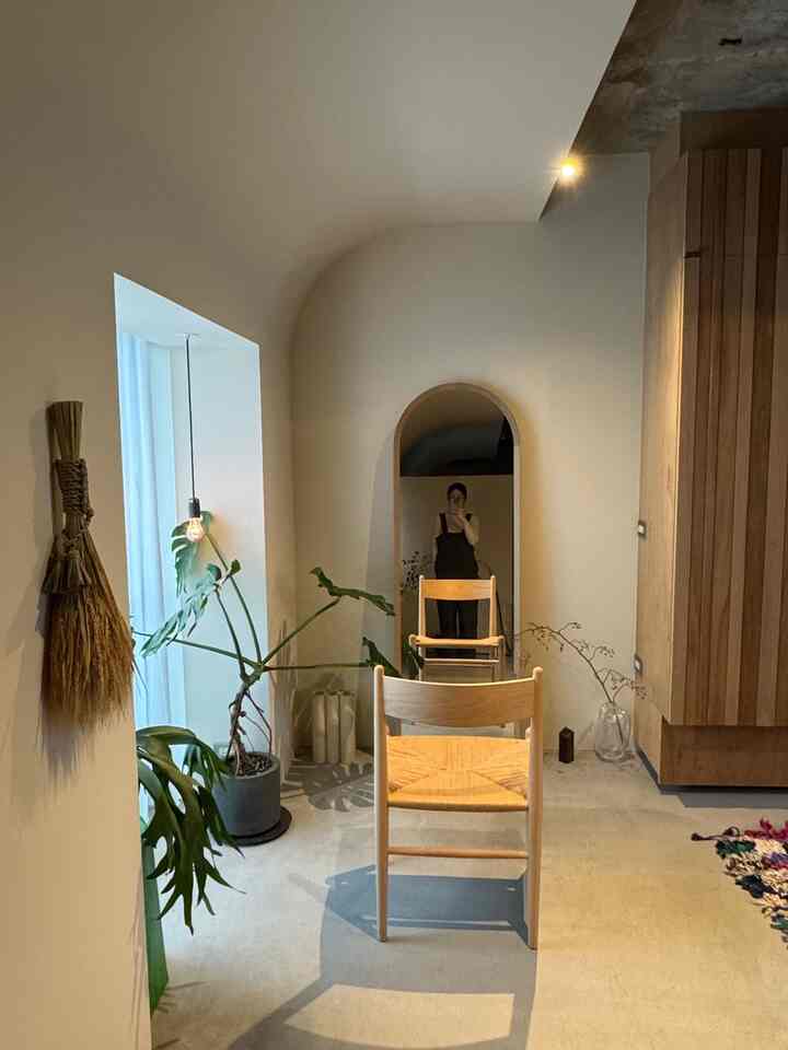 温かみのあるナチュラルトーンの玄関、木製の椅子と植物が配置された雰囲気のあるインテリア