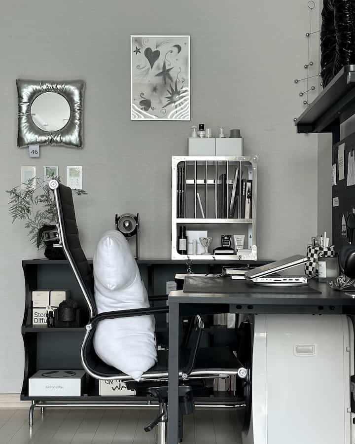 Modern minimal home office with gray walls and black furniture, featuring a desk and office chair as focal elements amid neat interior accessories