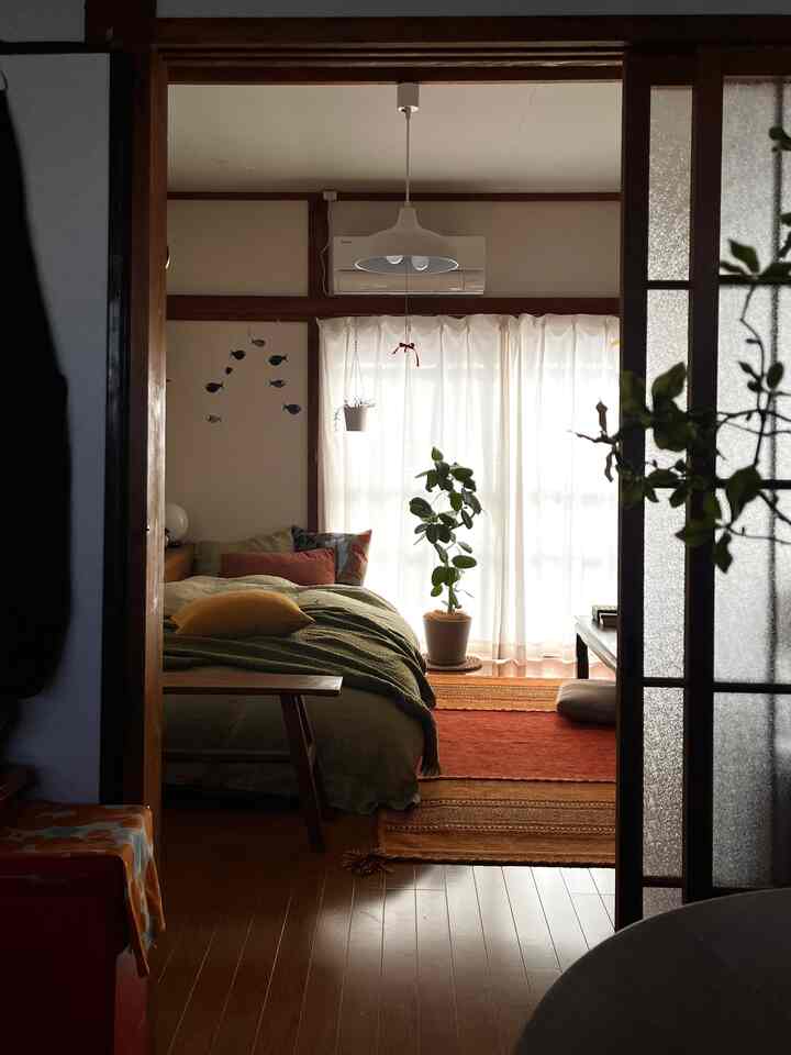 Warm wood-tone bedroom featuring natural green plant, pendant light, and cozy orange rugs creating a inviting atmosphere