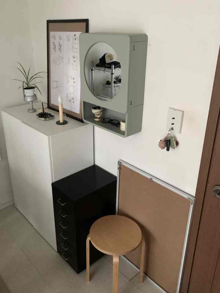 ホワイトとブラック、ウッドトーンが調和した狭い玄関スペース、木製スツールと収納棚、壁掛けミラーが配された自然な雰囲気のインテリア