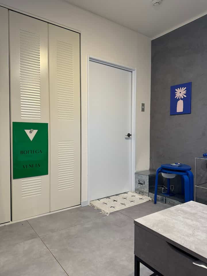 A gray and white toned living room featuring blue stools and a console table with a clean and modern atmosphere