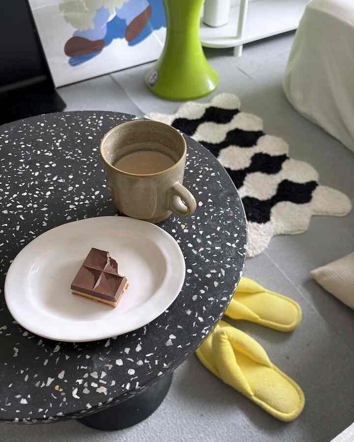 黒と白の色調の8畳寝室、サイドテーブルにコーヒーカップとチョコレート、黄色いスリッパが置かれた雰囲気のある空間