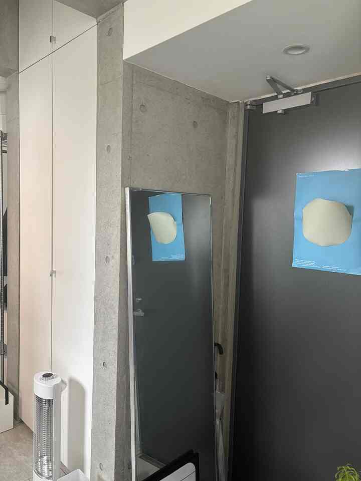 グレーのコンクリート壁と白い壁、全身鏡が配置されたモダンな玄関空間