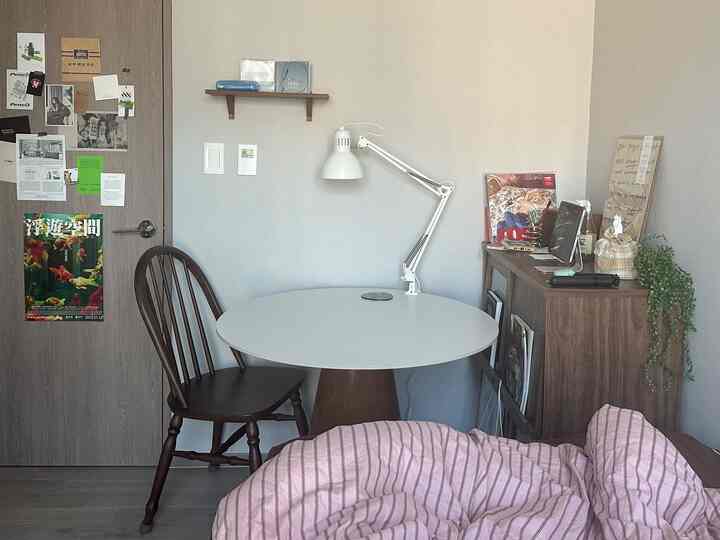 ナチュラルな色調の小さな寝室、木製家具とピンクの寝具が調和した雰囲気のある空間