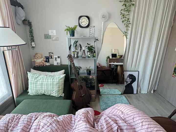 グリーンのソファと植物が配置された小さな寝室、ヴィンテージ感のある落ち着いた空間