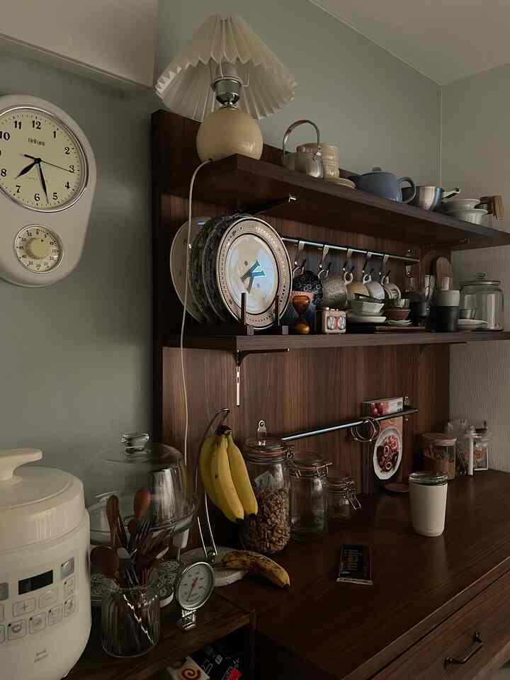 ダークな木目調とレトロスタイルの一人暮らし用キッチン、ヴィンテージの装飾と時計が配された雰囲気のある空間