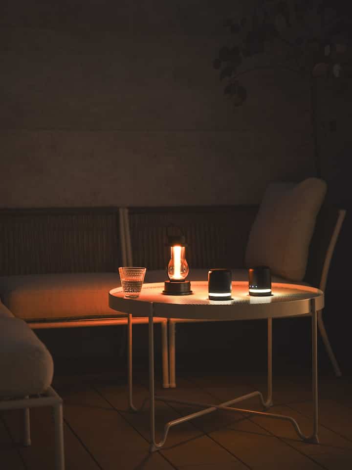 暖かいゴールドトーンの光が映える白いバルコニー空間、コーナーソファとコーヒーテーブルが落ち着いた雰囲気を作り出している。