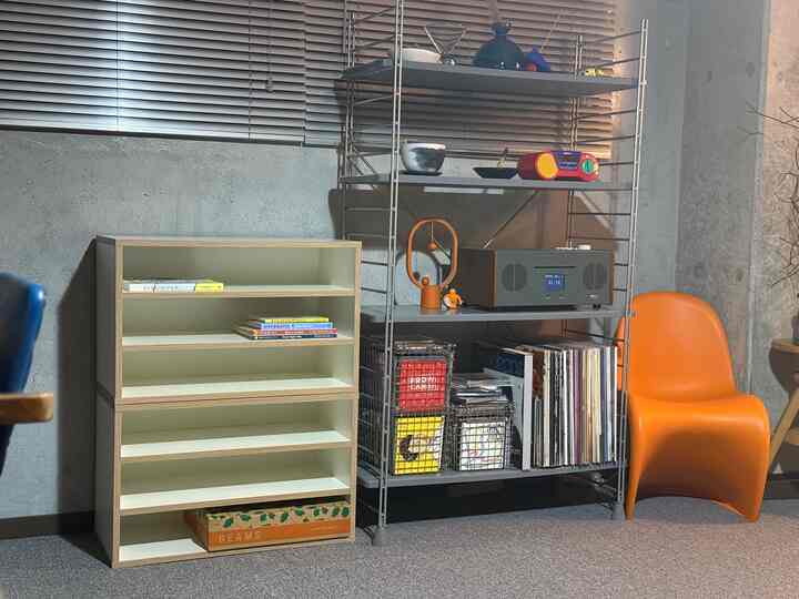 白とオレンジの色調の書斎、オープンラックと本棚が配置された実用的でミニマルな雰囲気のインテリア