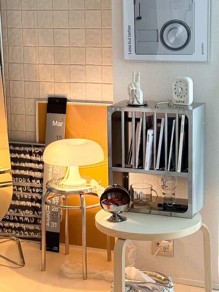 シルバーとイエローの調和が取れた小スペース、金属製の棚とスツールの上に灯されたランプが温かみのある雰囲気を演出するインテリア