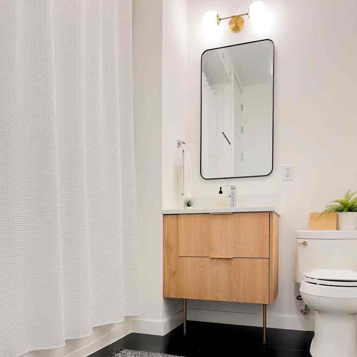 White and wood tone powder room featuring a mirror and vanity with a clean, modern bathroom atmosphere