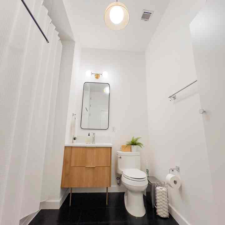 White and natural toned mid-century modern bathroom featuring wood vanity and clean rectangular mirror with a fresh atmosphere