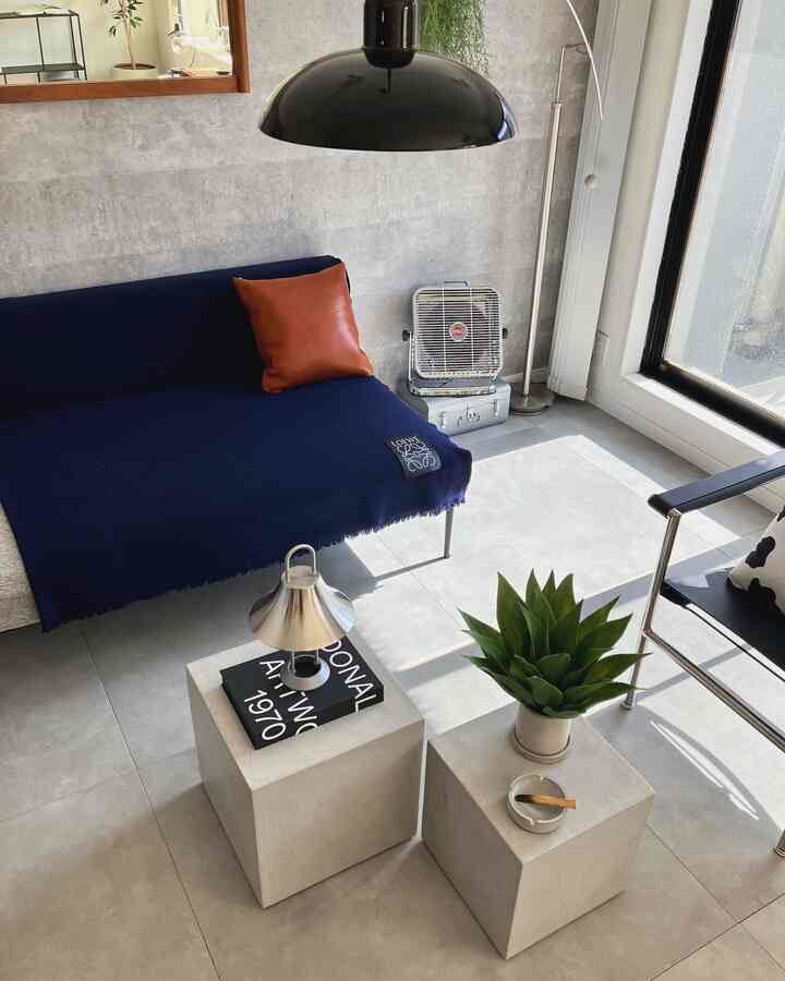Modern mid-century modern living room with gray walls and navy sofa, featuring concrete cube side tables and a floor lamp